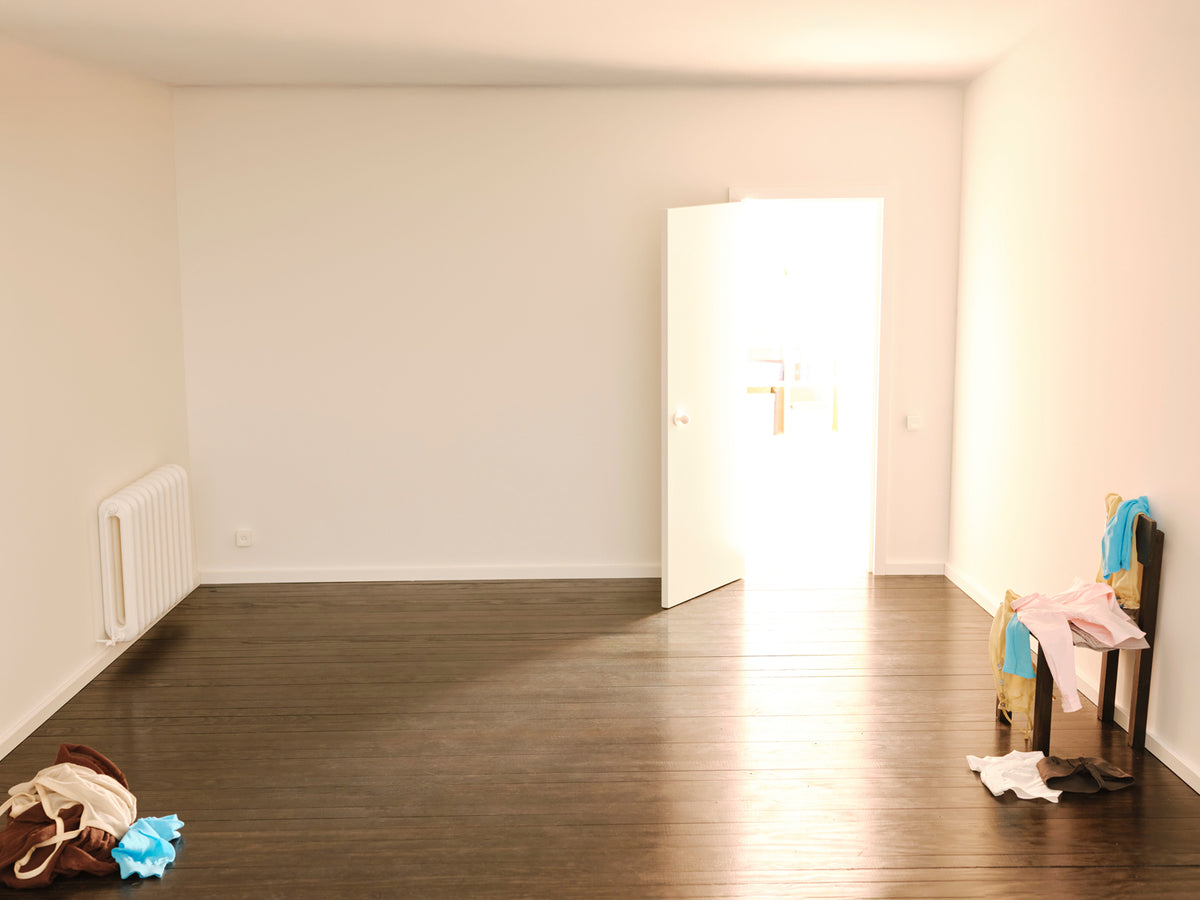 An empty white campaign room with Paloma Wool clothes arranged around its edges
